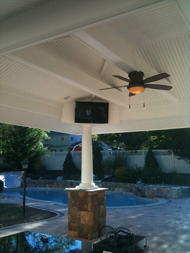 A ceiling fan and television in a covered outdoor space.